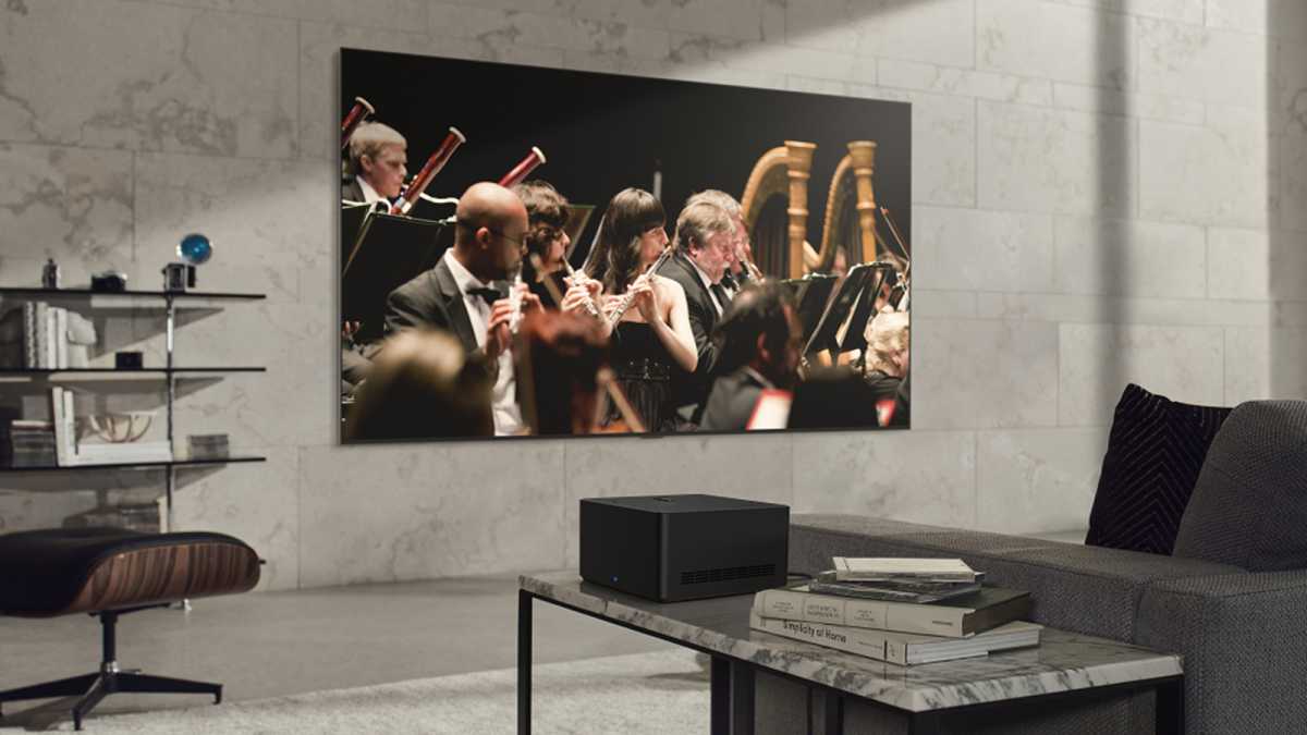 Televisor inalámbrico LG Signature OLED M en la pared de la sala de estar reproduciendo un video de una orquesta