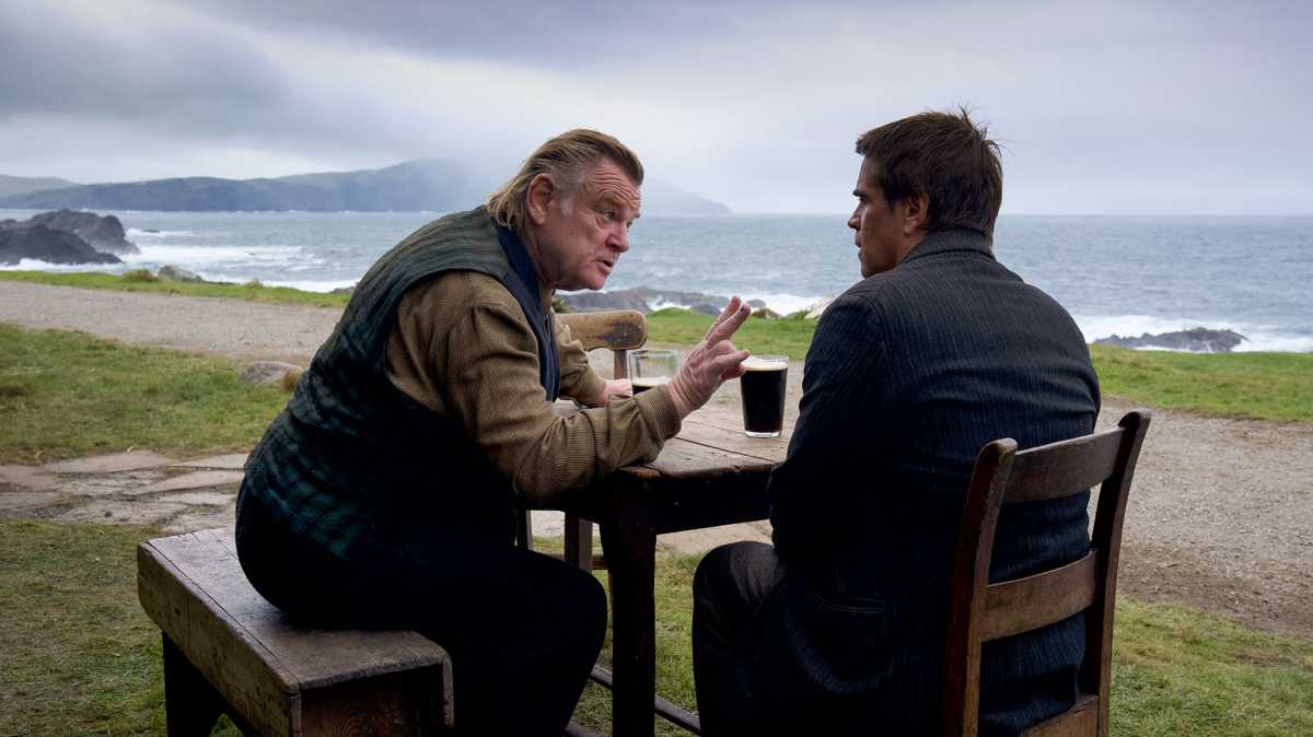 Las Banshees de Inisherin - Colin Farrell y Brendan Gleeson sentados en una mesa bebiendo Guiness en la playa