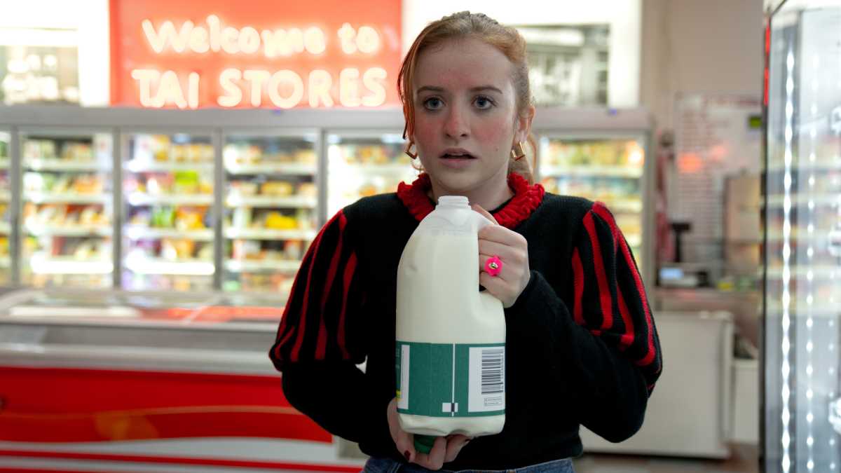 Jen en la serie de Disney+ Extraordinaria sosteniendo una botella de leche