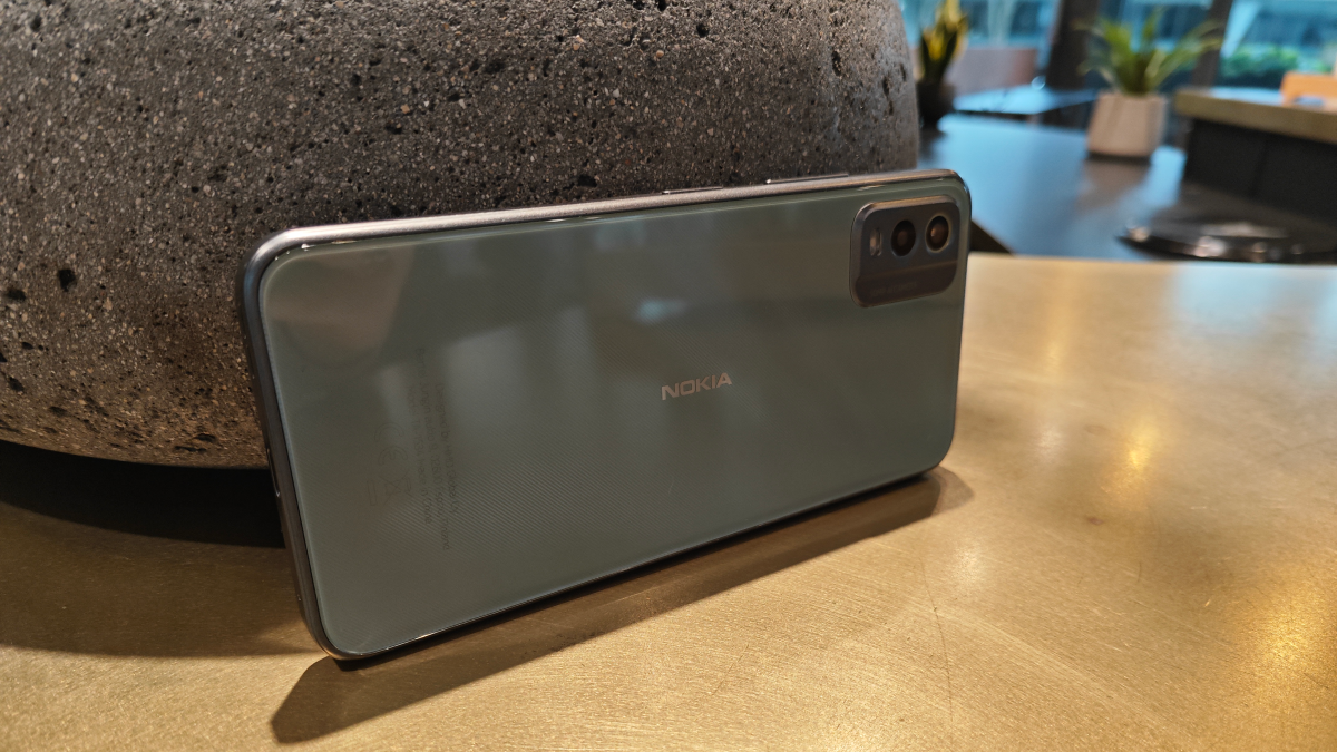 Nokia C32 verde apoyado contra una roca sobre una mesa