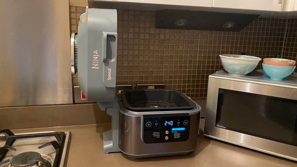 Ninja Speedi con la tapa hacia arriba, mostrando que se abre debajo de un gabinete de cocina