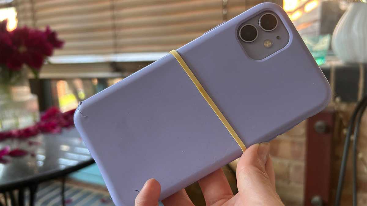 Un iPhone 11 en una funda dañada con una banda elástica enrollada alrededor